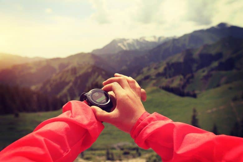 young woman hiker checking the altimeter on sports watch at mountain peak